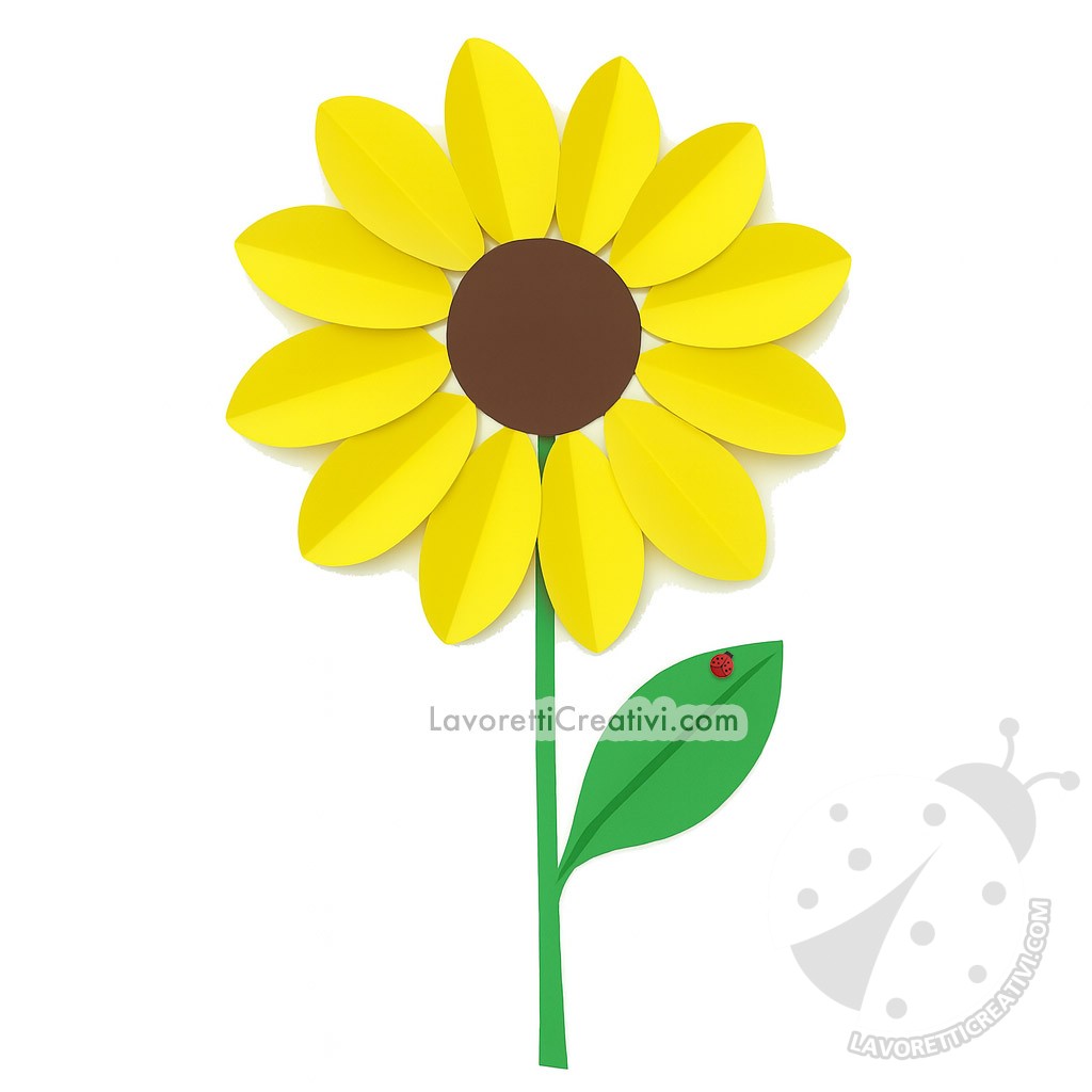 Girasole di carta con petali ovali gialli e centro marrone, montato su un gambo verde con foglia, realizzato come lavoretto estivo per bambini.
